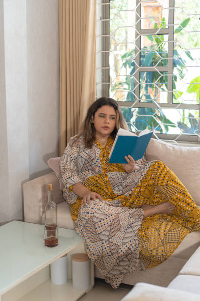 Distressed Latina woman reading a book on the sofa