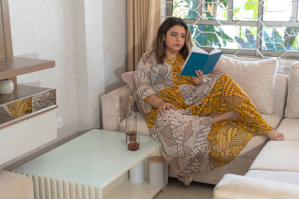 istock Distressed young woman reading a book on the sofa 1550541795