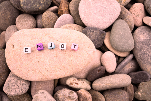 Enjoy word on pebble stone for background and inspiration