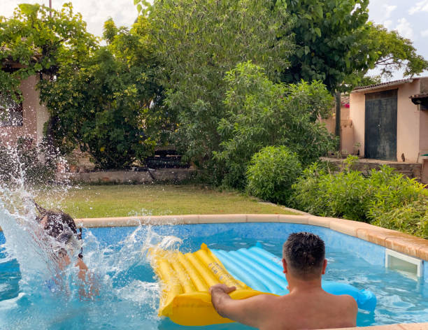 istock Carefree daughter and his father having fun while jumping in the pool 1550578620
