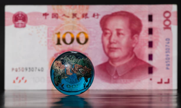 istock Glass globe in front of a 100 Chinese yuan banknote 1550580206
