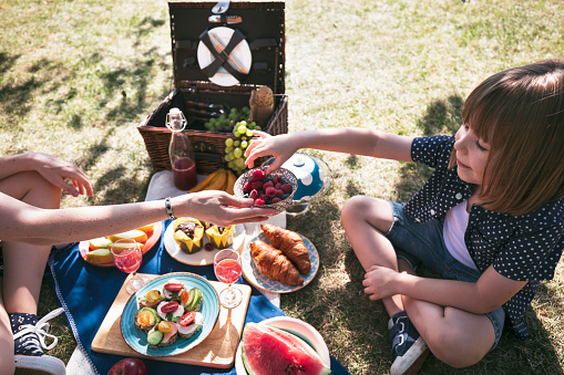 Happy mother and child enjoying picnic. Healthy food. Fruits. Vegetarian food. Raspberries.