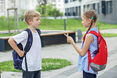 Two children, classmates, quarrel and yell on way from school. Conflict and negative emotion.