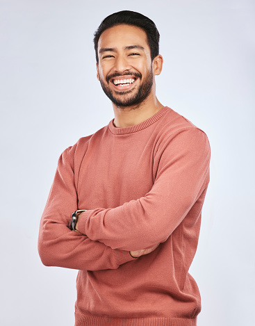 Portrait, happy or Asian man laughing with arms crossed or smile in studio in casual fashion or clothes. Relax, confidence or handsome male person smiling on white background with pride, humor or joy
