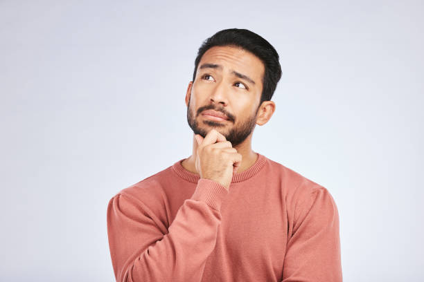 istock Face, man and thinking of idea in studio or planning, decision and choice with white mockup background. Asian male, model and curious with doubt, questions or thoughtful guy, confused or remember 1550595136