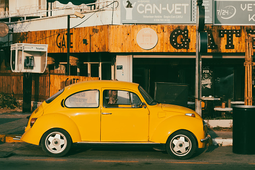 3 July 2023 - Turkey, Kuşadası. A classic retro car, VW Beetle,  parked on a street. Vintage yellow car. Side view.