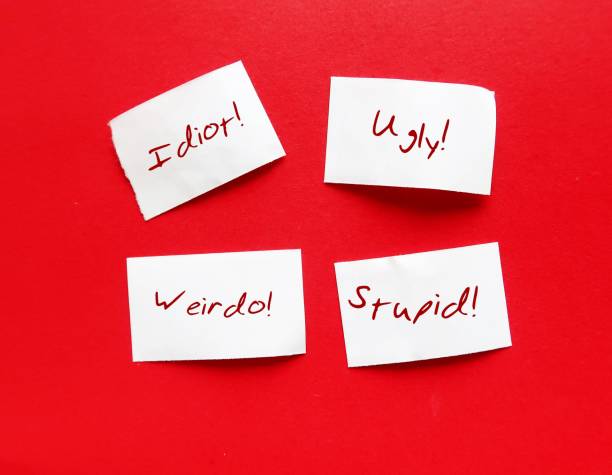 istock Torn paper pieces on red background with bully words UGLY STUPID WEIRDO IDIOT, concept of someone who hurts or frightens victims by degrade or demean in some way to feel powerful or stronger 1550630558