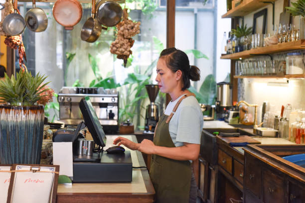istock Young Vietnamese waitress working with check out machine in cafe 1550642050