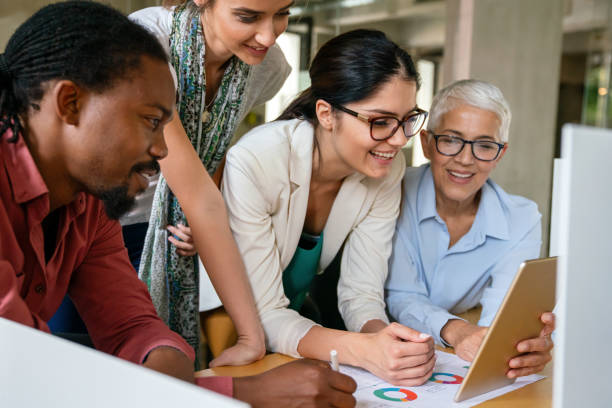 istock Smiling diverse colleagues gather in boardroom brainstorm discuss financial statistics together 1550665396
