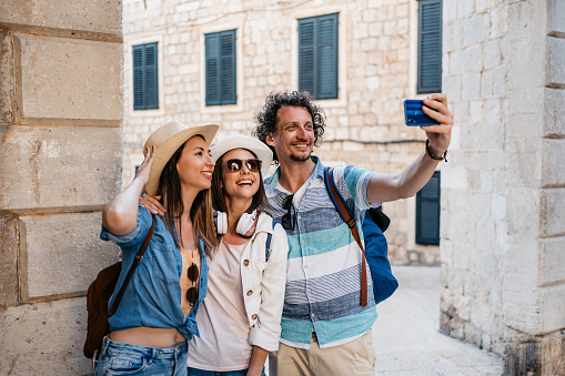 Three young tourists taking selfies using smart phone on the town square in Dubrovnik in Croatia.