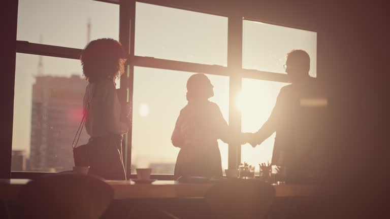 Business people, morning and handshake for meeting, partnership or b2b deal in agreement at the office. Group of employee shaking hands in sunrise for greeting, teamwork or collaboration at workplace