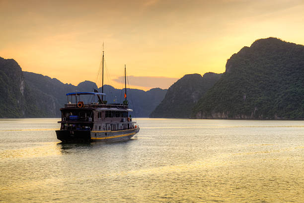 Vietnamese Junk cruising Halong Bay, Hanoi Vietnam sunset stock photo