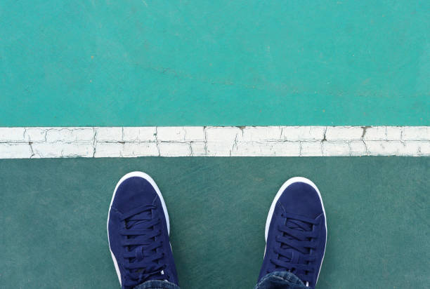 View of sneakers on asphalt road, man moving forward