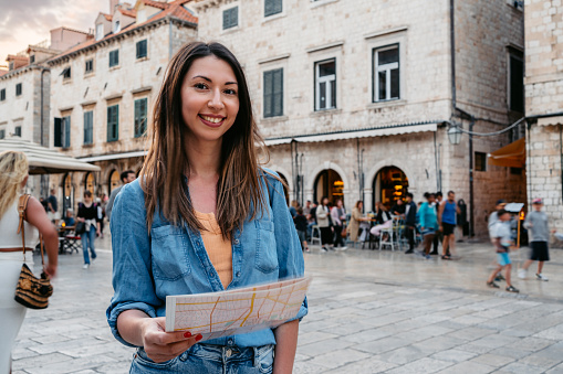 Portrait of a young female tourist reading a map on the street in Dubrovnik in Croatia.