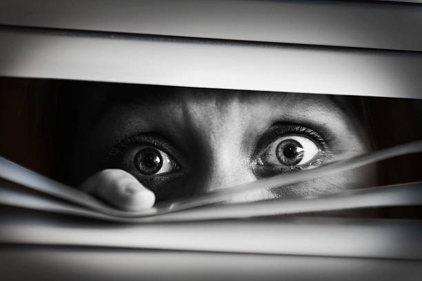 przerażona kobieta peeping przez zamknięty venetian ślepej próby. czarny i biały - shut in zdjęcia i obrazy z banku zdjęć