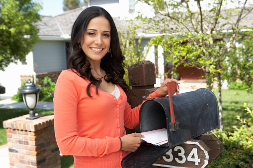 Hispanic Woman Checking Mailbox Smiling at Camera