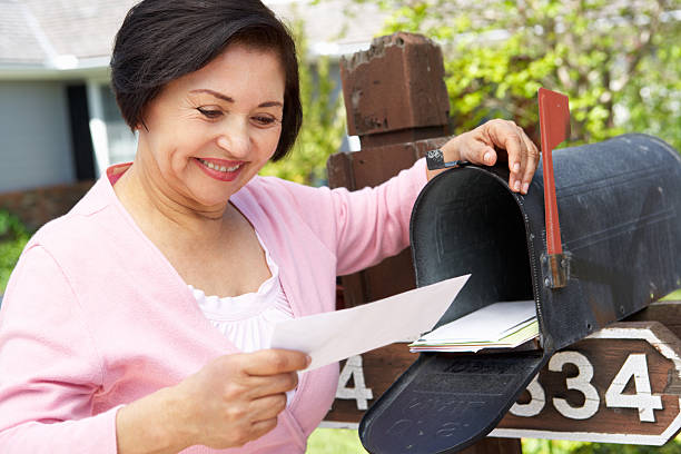 Smiling older Hispanic woman checking her mailbox Senior Hispanic Woman Checking Mailbox Smiling mailbox photos stock pictures, royalty-free photos & images