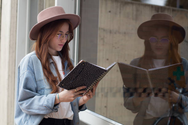 istock beautiful young student woman reading a book in a university library 1550717571