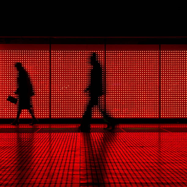 Silhouettes walking on a Moving sidewalk in red & black