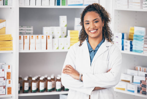 Pharmacy, pharmacist or portrait of woman with arms crossed or smile in customer services or clinic. Healthcare help desk, wellness or happy doctor smiling by medication on shelf in drugstore stock photo