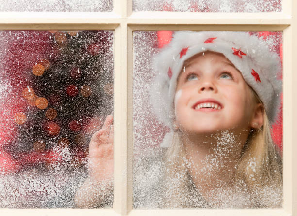 istock happy girl looking through snowy window at Christmas 155072921