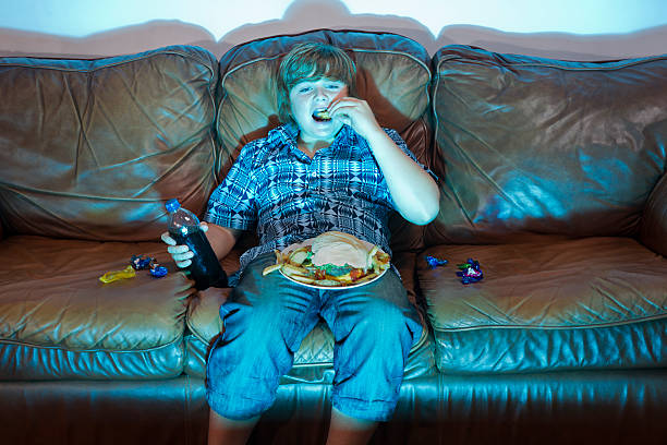 alimentation lourde - overweight child television laziness photos et images de collection