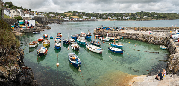 Coverack, Cornwall, UK - July 27, 2023.   Landscape view of traditional Cornish fishing boats moored in the tidal harbour of the quaint fishing village of Coverack with copy space