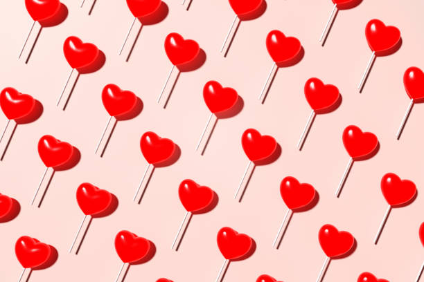 istock Heart shaped red lollypop seamless pattern on pink background. Top view. 1550749896