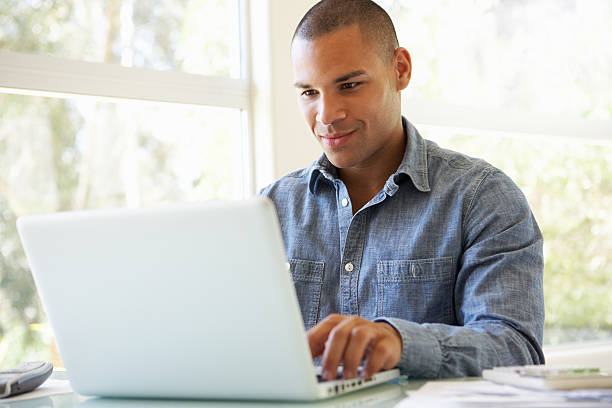 giovane uomo utilizzando un computer portatile a casa - men casual looking at camera one young man only foto e immagini stock