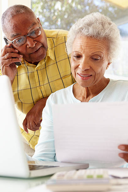 istock Senior couple looking at bills and using laptop 155075277