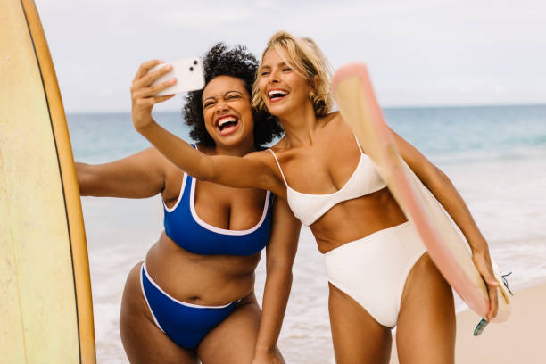 istock Summer surf fun: Female surfers taking a selfie on the beach 1550753718