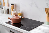 Clean black induction stove with control panel near marble countertop