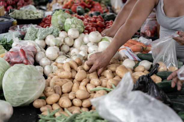 uma mulher hispânica adulta está escolhendo batatas em um mercado de rua - horizontal guatemala leaf vegetable market - fotografias e filmes do acervo