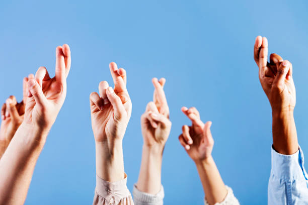 istock Six superstitious hands, all with fingers crossed, against blue 155076755