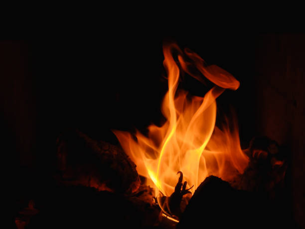 istock Fireplace burning with firewood logs. Fire flames on black background. Fireplace flames in winter 1550787676