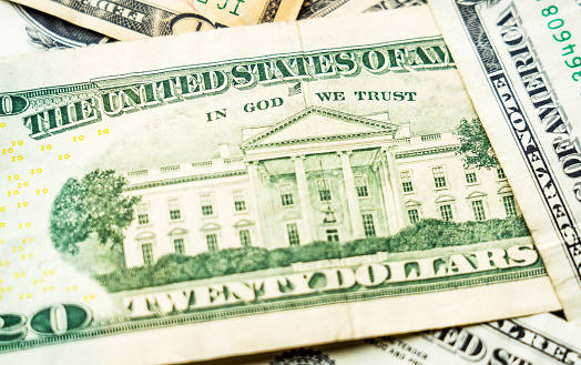 Macro image of part of a twenty dollar banknote, featuring the White House in Washington DC, with the quote \