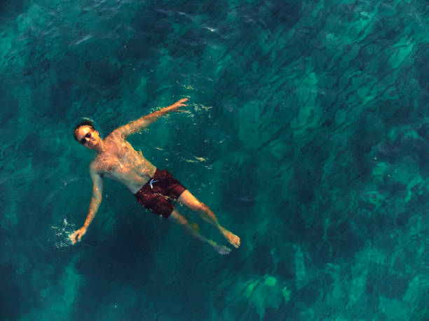 homem flutua de costas na água relaxante aérea - floating on water swimming pool men water - fotografias e filmes do acervo