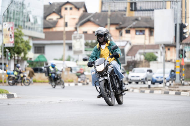 Man riding motorbike around traffic circle in Nairobi Early 30s rider on 350cc electric vehicle powered by smart battery embedded with IOT chips, part of E-mobility solution for rapidly developing African cities. kenyan man stock pictures, royalty-free photos & images