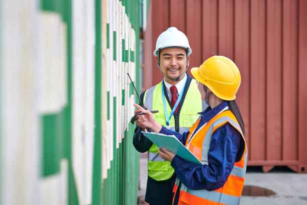 istock Two Asian Coworker Examining Information at Cargo Container 1550944259