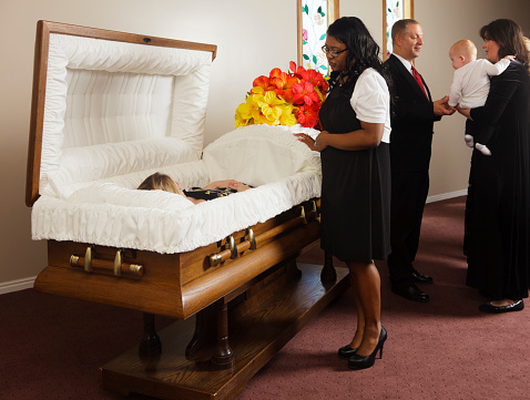 A receiving line of guests next to the casket at a funeral in a funeral home.