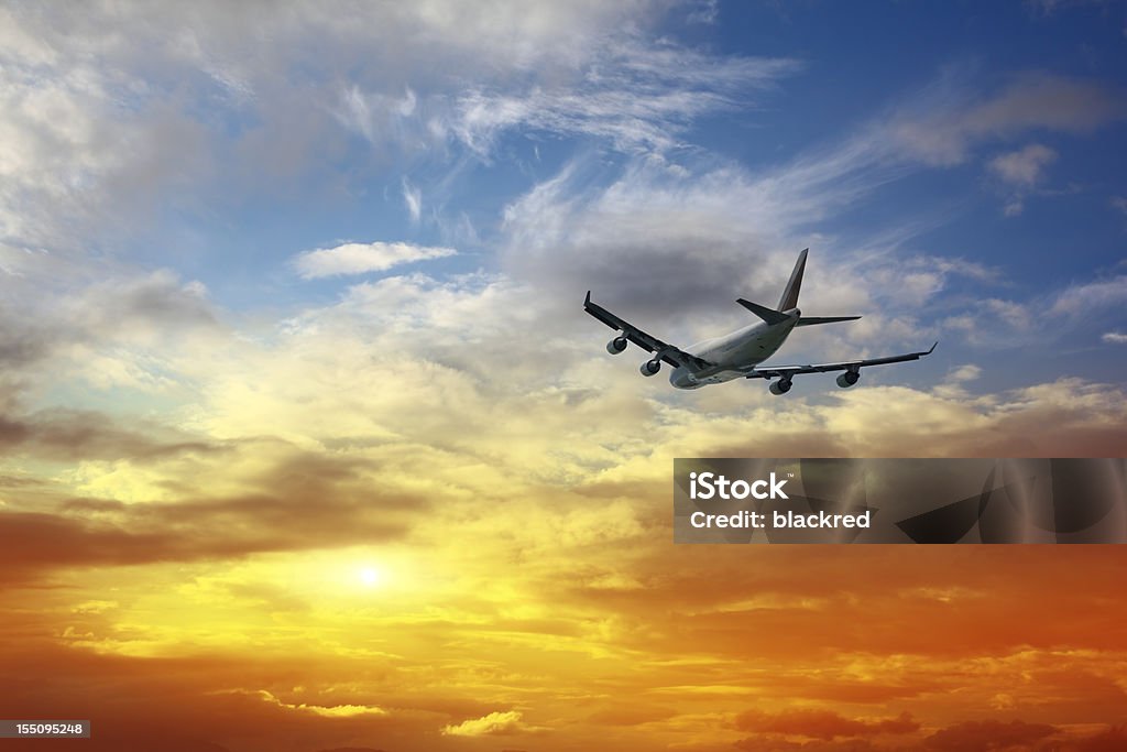 Airplane Flying into Sunset Sky Airplane taking off, flying into sunset cloudscape. Airplane Stock Photo