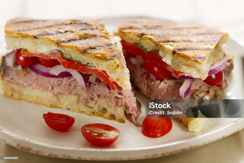 Panini Sandwiches Hot off the grill panini sandwiches made with crusty, hand sliced ciabatta bread, roast beef, red onions, cherry tomatoes, roasted bell pepper slices, and italian Fontina cheese. Panini Stock Photo