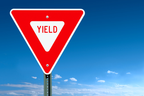 A yield road sign post over a clear blue sky with some clouds at the horizon - a clipping path is included to separate sign from bkg.