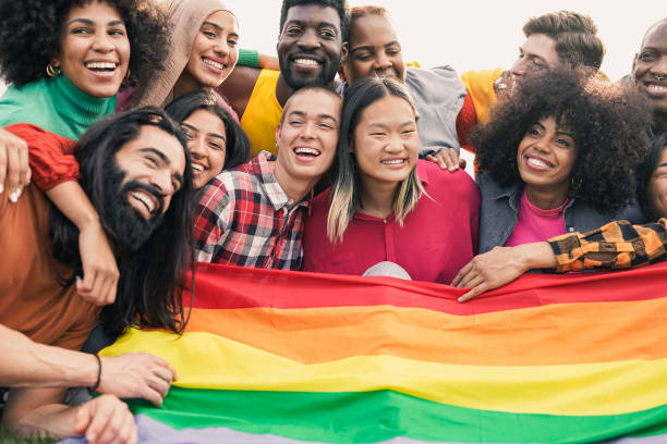istock Young diverse friends having fun holding LGBT rainbow flag - Multiracial people hugging each other at pride parade 1550954341