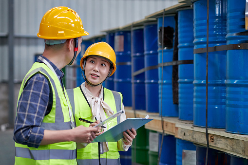 Two asian warehouse inspector examining and discussing in chemicals warehouse.