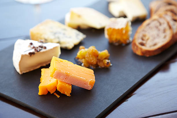 Fancy cheese plate with bread and honey Fancy cheese plate with blue cheese, cheddar, goat cheese, bread, honey and pistachios at a luxury restaurant.  Horizontal shot. plate fig blue cheese cheese stock pictures, royalty-free photos & images