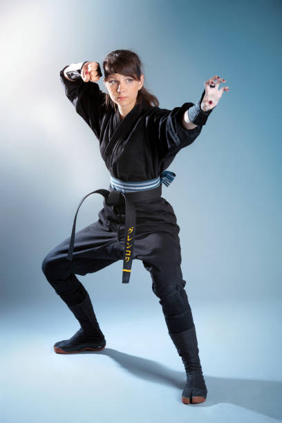 Brunette young woman in black japanese clothes standing in fighting stance
