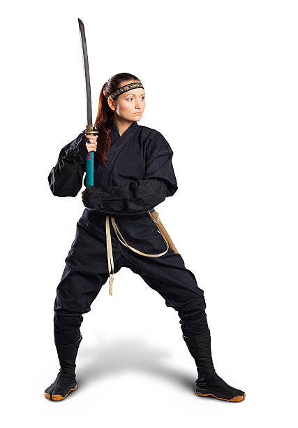 Yong woman standing in fighting stance. Isolated on white A brunette girl performing a kenbu movement with a katana. Kenbu is a japanese dance performed with a sword, traditional clothes and various accessories.  warrior person stock pictures, royalty-free photos & images