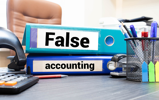 FALSE ACCOUNTING text words inscription on mint folder with folder calculator pen on glossy white background. ACCOUNTING FRAUD concept