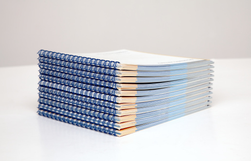 stack of booklets with blue wire-o binding on a table